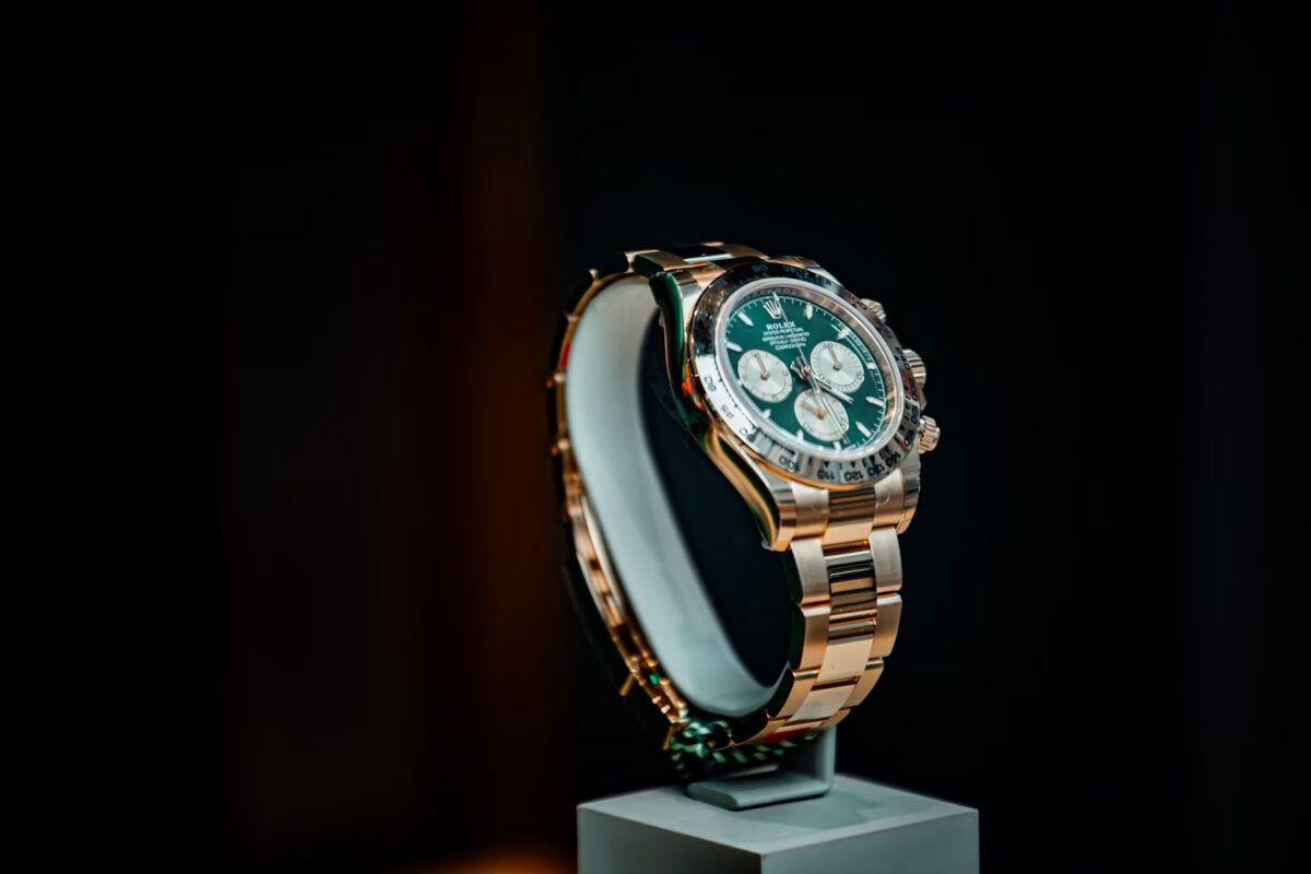 Rolex Cosmograph Daytona con esfera verde, tres subesferas y pulsadores del cronógrafo sobre un expositor oscuro