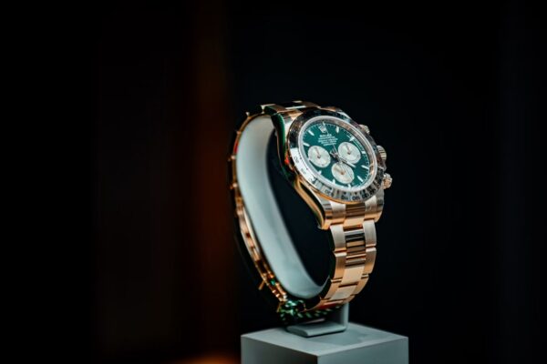 Rolex Cosmograph Daytona con esfera verde, tres subesferas y pulsadores del cronógrafo sobre un expositor oscuro