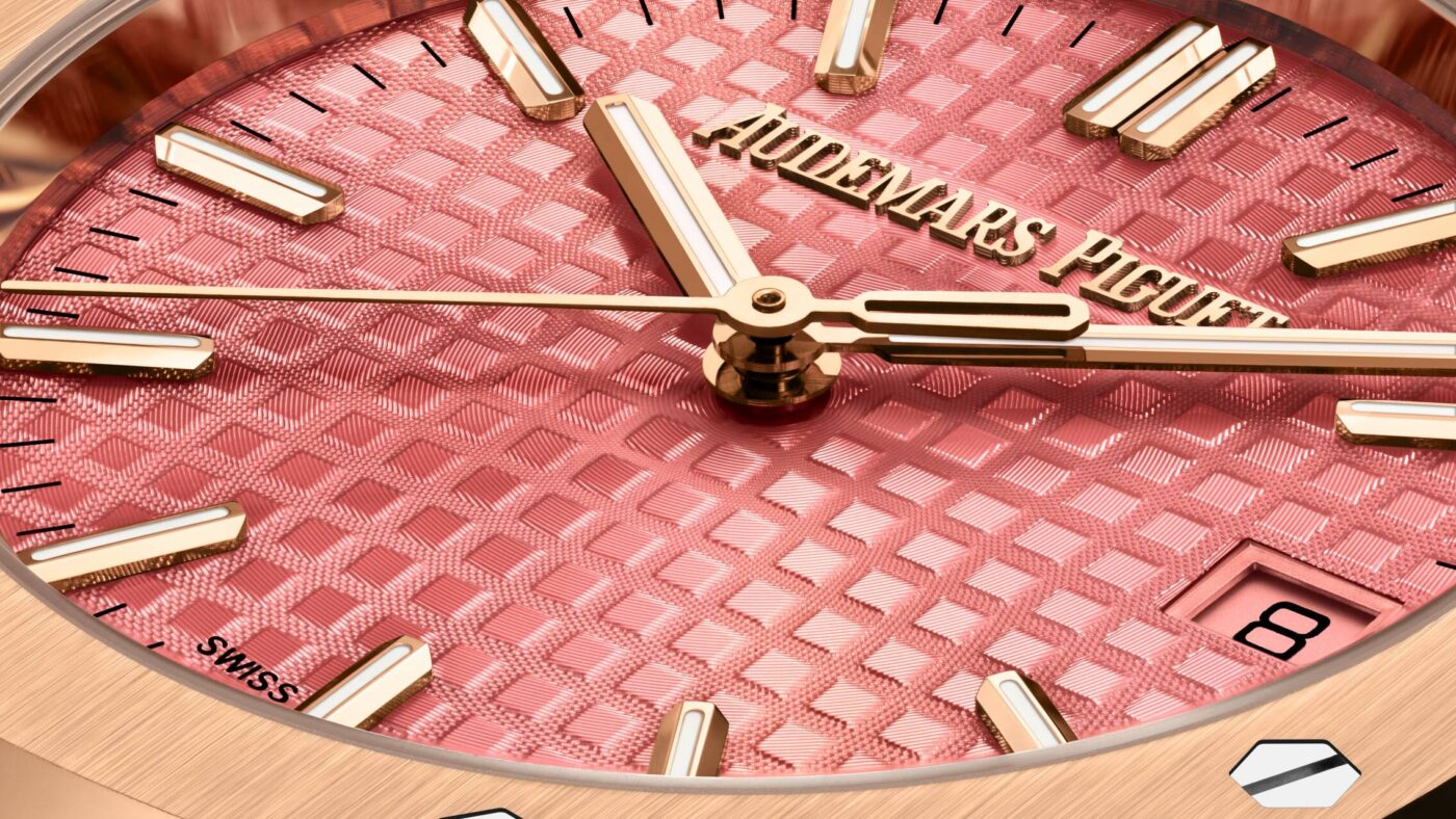 Detalle de una esfera rosa Audemars Piguet Royal Oak con relieve Tapisserie, agujas e índices dorados y ventana de fecha.